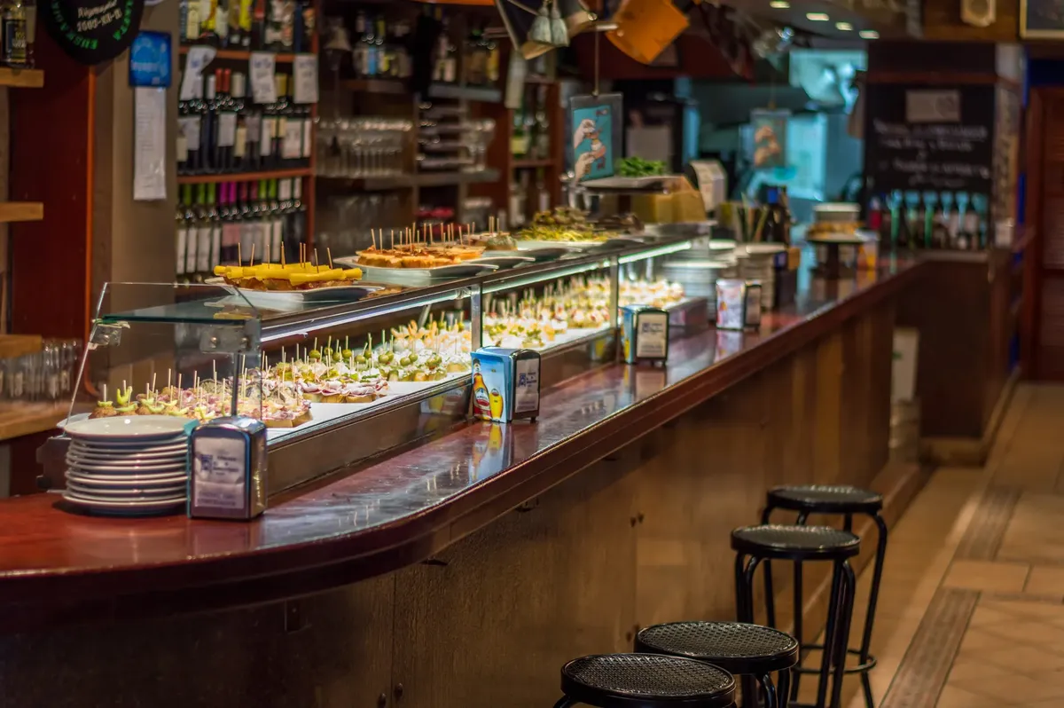 Explore a vibrant tapas bar in Barcelona with a wide selection of pinchos on display.