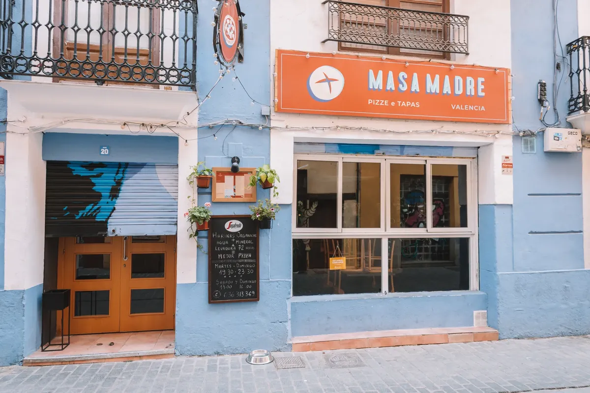 Colorful street view of Masa Madre pizza and tapas restaurant in Valencia, Spain.